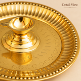 Detailed close-up view of a traditional brass diya with attached pooja plate highlighting the polished golden brass oil lamp cup, raised pedestal base, engraved star and curved decorative patterns, fluted plate border and rounded beaded rim detailing. The image showcases the reflective brass finish and decorative craftsmanship of the 13-inch pooja thali, suitable for traditional aarti ceremonies, daily worship and festive religious arrangements.