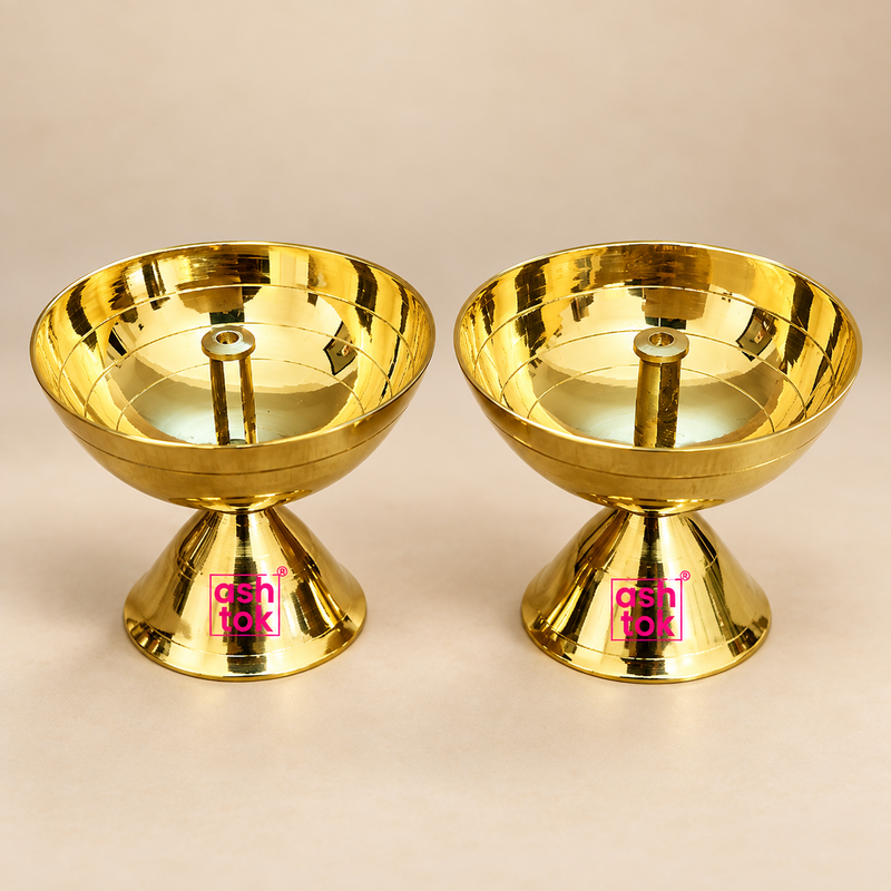 Brass diya for pooja featuring a polished golden bowl, central wick holder and stable pedestal base, presented as a matching pair on a premium beige studio background for Diwali, daily worship and traditional home temple use.