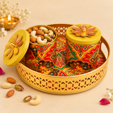 Brass gift tray with two decorative lidded bowls used as a festive serving set, styled with assorted dry fruits on a beige background.
