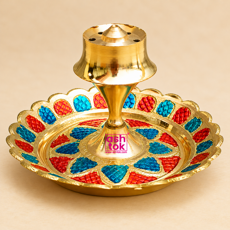Traditional Brass Incense Stick Holder featuring a polished golden brass finish, circular decorative tray with vibrant red and blue Meenakari-style detailing, scalloped edges and a raised central agarbatti holder with multiple incense stick holes. Measuring 3.5 inches in diameter and 2 inches in height, this decorative brass agarbatti stand is suitable for daily pooja, home mandir decoration, incense burning, religious ceremonies, festive arrangements and traditional Indian home decor.