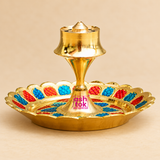 Side view of a decorative Brass Incense Stick Holder showing its raised polished golden brass central stand, flared incense holding top, narrow connecting stem and wide circular decorative tray. The tray features scalloped golden edges with vibrant red and blue Meenakari-style patterns along the surrounding border. This traditional agarbatti holder measures 3.5 inches in diameter and 2 inches in height, making it suitable for daily incense burning, pooja room decoration, meditation areas and traditional Ind