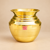 Polished brass kalash with a wide flared mouth, rounded body, decorative neck rings and subtle horizontal line detailing, professionally presented on a premium beige studio background for puja, mandir and ritual use.