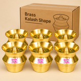 Set of six Brass Kalash Shape pooja holders arranged together with simple brown cardboard packaging against a premium beige studio background. Each golden brass holder features a broad circular flared rim, raised central projection, multiple round openings, smooth curved kalash-shaped body, and decorative horizontal grooves. Measuring 2 inches in height and 2 inches in diameter per piece, these compact traditional brass accessories are suitable for bulk pooja supplies, religious return gifts, temple require