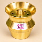 Elevated angle photograph of a polished Brass Kalash Shape pooja accessory showing its golden brass exterior, flared circular opening, raised central projection, multiple round holes, engraved horizontal grooves, and gracefully curved kalash-inspired silhouette. Designed with a compact 2-inch height and 2-inch diameter, this traditional brass holder complements home temple decoration, daily religious ceremonies, and festive worship arrangements.