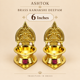 Brass Kamakshi Deepam set of 2 in a refined beige product display, labeled as the 6 inch size variant. The image features two traditional brass lamps with detailed Kamakshi-style backplates, wide oil bowls, and polished bases placed neatly side by side. The longer height gives the deepams a more prominent devotional appearance, making them suitable for pooja rooms, festive worship setups, traditional gifting, and elegant home temple arrangements.


