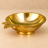 Detailed close-up photograph of a traditional Brass Kuber Diya showcasing its smooth polished golden brass interior, beautifully rounded shallow oil reservoir, distinctive pointed wick spout, finely finished circular rim, and intricate floral and leaf engravings decorating the outer bowl surface. The close-up highlights the traditional craftsmanship, reflective golden metallic finish, decorative side detailing, and compact circular pedestal base. This brass pooja oil lamp measures 3 inches in length, 2.5 in