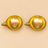 Detailed top-view photograph of Brass Kuber Diya Set of 2 Pcs showcasing two identical traditional golden brass oil lamps with smooth circular bowl-shaped interiors, broad polished rims, and decorative pointed wick spouts extending outward from one side of each diya. The elevated perspective highlights the symmetrical oil reservoirs, reflective golden brass surfaces, and distinct tapered spout design.