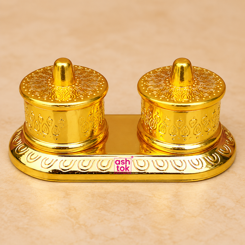 Brass Kumkum Box with two round covered compartments on a decorative oval base, featuring embossed traditional patterns, polished golden finish and individual lids, professionally presented on a premium beige studio background for puja and home temple use.