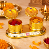 Brass Kumkum Box shown in a traditional puja setting with the two compartments open and filled with red kumkum and yellow haldi, surrounded by diya and floral decorations for home temple, festive rituals and religious ceremonies.