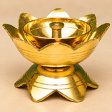 Detailed close-up photograph of a traditional Brass Lotus Diya highlighting its elegant polished golden brass finish, beautifully formed upward-facing lotus petals, smooth reflective circular oil reservoir, and raised cylindrical central wick holder with a round opening. The image captures the carefully shaped lotus flower edges, fine decorative horizontal grooves around the outer bowl, and matching lotus-petal pedestal base. The intricate floral design and golden metallic surface make this brass pooja diya