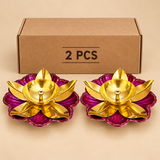 Set of 2 decorative brass lotus diyas displayed in front of a plain cardboard packaging box, featuring a shiny golden brass oil bowl, elegantly shaped lotus petals and a bright pink floral base. Beautiful traditional oil lamps for home temple decoration, Diwali puja, festive celebrations and return gifts.