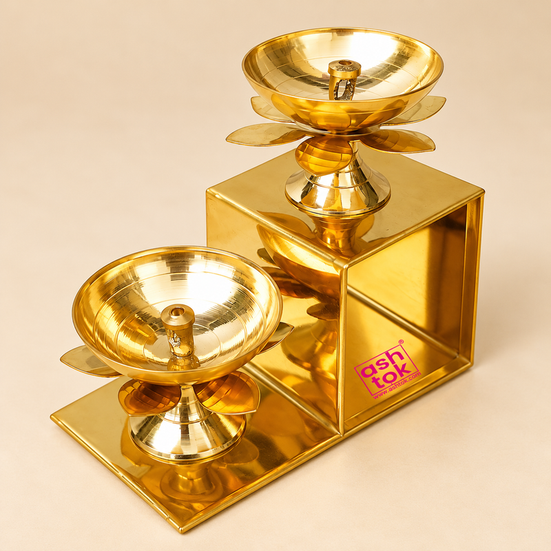 Traditional Brass Lotus Diya with Stand featuring a beautiful two-step geometric design, polished golden brass finish and two elevated lotus-shaped oil lamps arranged at different heights. Each diya features a smooth rounded oil bowl with a central wick holder, decorative lotus petals beneath the bowl and a beautifully shaped pedestal. The sturdy rectangular stepped brass structure creates an elegant tiered display suitable for home decoration, pooja rooms, festive lighting, Diwali celebrations, decorative 