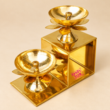 Traditional Brass Lotus Diya with Stand featuring a beautiful two-step geometric design, polished golden brass finish and two elevated lotus-shaped oil lamps arranged at different heights. Each diya features a smooth rounded oil bowl with a central wick holder, decorative lotus petals beneath the bowl and a beautifully shaped pedestal. The sturdy rectangular stepped brass structure creates an elegant tiered display suitable for home decoration, pooja rooms, festive lighting, Diwali celebrations, decorative 