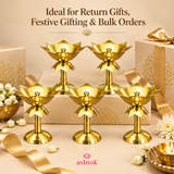 Multiple Brass Lotus Stand Diyas arranged in an elegant gifting setup with decorative gift boxes, ribbons, flowers and beige styling, highlighting the product as a suitable choice for return gifts, festive gifting, wedding gifting, event giveaways and bulk orders, with its polished brass finish and lotus-inspired traditional design clearly visible.