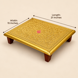 Traditional Brass Marriage Chowki size guide displaying a rectangular handcrafted golden brass sheet platform measuring 21 inches in length and 15 inches in width. The decorative chowki features an intricately embossed floral surface, detailed ornamental border, polished golden edges and four sturdy dark brown wooden supporting legs. Measurement arrows indicate the dimensions of the rectangular platform against a clean beige studio background.