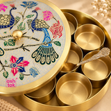 Close-up image of brass masala box showing the intricate meenakari artwork on the lid, smooth brass compartments, spoon detail and polished brass finish, highlighting the craftsmanship and elegant traditional design of the spice container.
