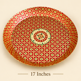 Product dimension diagram displaying a top-down and profile view of a round handcrafted brass tray with red and gold Meenakari floral artwork. Black arrows indicate a diameter of 17 inches and a side wall height of 2.5 inches against a beige background.