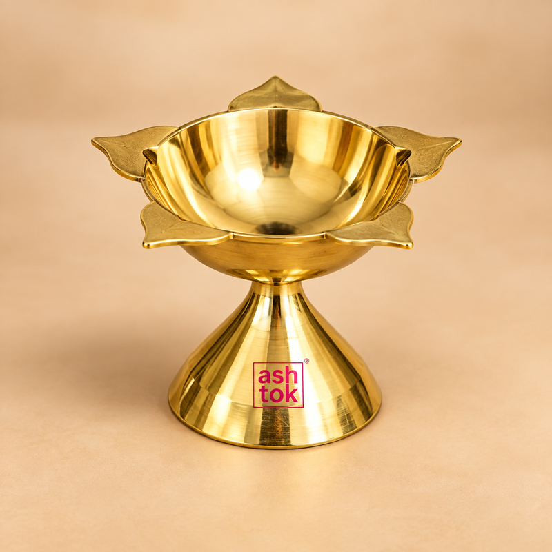 Polished brass Panch Batti Diya displayed as a single traditional oil lamp on a clean warm beige studio background. The diya features a lotus-inspired upper bowl with five outward-facing wick points, a smooth deep central oil reservoir and a stable flared pedestal base that gives the lamp an elegant balanced appearance. The rich golden brass finish reflects soft studio lighting and highlights the curved bowl, five petal-shaped wick holders and classic traditional profile. 