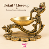 Close-up of brass diya with peacock handle showing intricate brass craftsmanship, engraved detailing and traditional design.