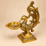 Side view of a traditional antique brass peacock diya displaying the sculpted peacock form and oil lamp bowl.