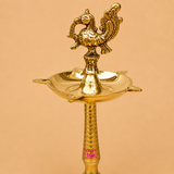 Close-up of a handcrafted brass peacock diya featuring an ornate peacock finial and traditional oil lamp bowl, ideal for pooja, temple rituals, Diwali celebrations, weddings, and festive home décor.