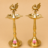 Pair of handcrafted brass peacock standing diyas with decorative peacock finial and traditional oil lamp design, ideal for pooja, temple, Diwali, housewarming, weddings, and festive home décor.