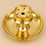 Original top view of a traditional brass diya with a broad polished circular plate, raised central pedestal and flower-shaped upper holder featuring a scalloped rim, multiple small round holes and a central opening, photographed from directly above to clearly show the concentric plate design, reflective brass surface and symmetrical functional construction for daily puja, oil lamp use, religious ceremonies and festive worship.