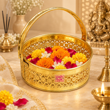Round Shaped Brass Puja Basket used as a traditional flower basket for puja, beautifully filled with marigold flowers, jasmine and rose petals in an elegant devotional setting. The golden basket features intricate phool butti cutwork, curved handle, polished brass finish and ASHTOK logo, making it suitable for home temple rituals, aarti, festivals, religious ceremonies and carrying flowers or offerings.