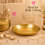 Promotional gifting setup titled 'Ideal for Bulk Gifting - TIMELESS CRAFTSMANSHIP MEANINGFUL CONNECTIONS' by Ashtok. A single brass hammered thali sits prominently in the center alongside a stack of four matching thalis, a premium beige gift box tied with a satin ribbon, a greeting card reading 'A Thoughtful Gift for a Brighter Tomorrow', and white jasmine flowers. Icons below highlight corporate gifts, weddings, festivals, and long-lasting quality.
