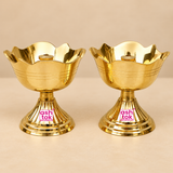 Two traditional Brass Rose Diyas displayed side by side on a premium beige studio background, featuring an elegant flower-shaped bowl with beautifully curved rose petal edges, a polished golden brass finish, and a central cylindrical wick holder designed for lighting during pooja rituals. Each brass diya features delicate horizontal engraved lines around the bowl, a sturdy fluted pedestal stand, and a broad circular stepped base with decorative concentric rings. The reflective golden surface highlights the 
