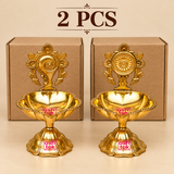 Brass Shanku Chakra Diya 2 pcs quantity image with two diyas placed in front of simple cardboard packaging on a beige background.