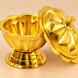 Detailed close-up view of a traditional brass sindoor box showing its polished golden surface, decorative flower-petal lid design, raised cylindrical knob and scalloped container body. The lid is positioned beside the open bowl to highlight its smooth interior, fluted walls and sturdy circular pedestal base. The image showcases the intricate floral detailing and traditional craftsmanship of this brass kumkum container for wedding rituals and puja ceremonies.