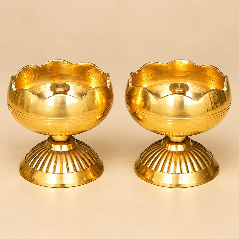 Two traditional Brass Tamatar Diyas displayed side by side against a premium beige studio background, featuring a polished golden brass finish, rounded tomato-shaped oil bowls, decorative scalloped flower-petal rims, central cylindrical wick holders, and sturdy fluted pedestal bases. Each brass diya measures 2 inches in diameter and 2.5 inches in height, making it a decorative oil lamp suitable for daily pooja, home mandir worship, Diwali celebrations, traditional ceremonies, and festive temple decoration.