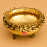 Handcrafted brass urli with decorative hanging bells and ornate legs, ideal for floating flowers, candles, pooja rituals, Diwali décor, weddings, housewarming, and traditional home decoration.