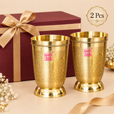 Set of 2 handcrafted brass water glasses displayed as a gift set with elegant presentation, featuring engraved floral detailing, polished golden finish and traditional drinkware styling, suitable for gifting, housewarming and special occasions.