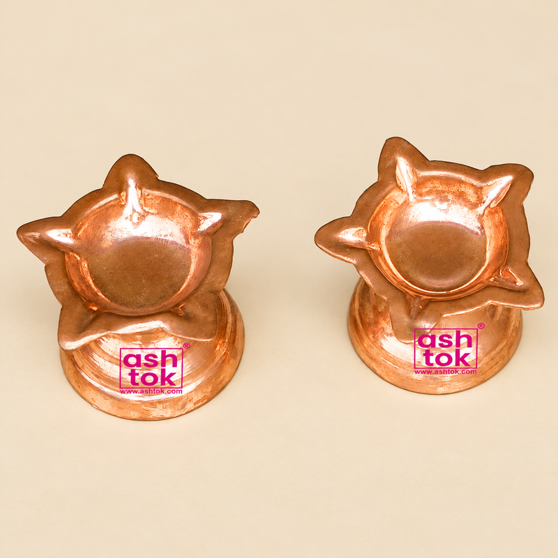 Set of six traditional Copper Diyas displayed together on a premium beige studio background alongside a simple brown cardboard packaging box, illustrating a practical bulk gifting and storage arrangement. The image features six matching flower-shaped copper oil lamps arranged neatly in two rows, with three diyas positioned at the back and three in the foreground. Each copper diya features an elegant shallow bowl surrounded by multiple pointed and curved floral petals, a polished reddish-orange copper finish