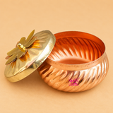 Open copper kalash shaped storage container with decorative brass lid on a beige studio background, handcrafted traditional kitchen storage box by Ashtok.