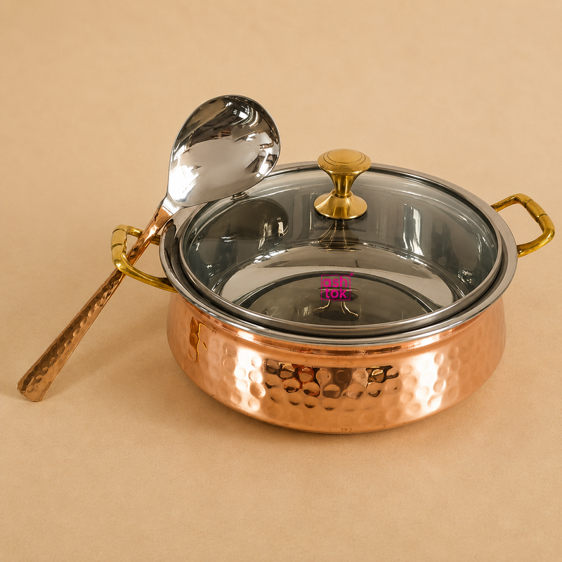 Hammered copper and stainless steel serving handi with transparent glass lid, brass handles, and matching serving spoon, ideal for serving biryani, curries, rice, and traditional Indian dishes at home, restaurants, and catering.