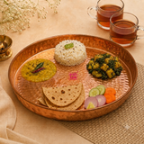 Ashtok copper hammered thali platter styled with an Indian meal of rice, dal, roti, vegetable curry, salad, and tea cups.