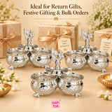 Multiple German silver chopala gift items displayed together in a festive gifting arrangement with decorative gift boxes, ribbons, flowers and warm beige styling, presented as a premium gifting option for return gifts, festive gifting, wedding gifting, bulk orders, event giveaways and special occasions, while clearly showing the product’s traditional triple-bowl design, embossed metal finish, central finial and elegant decorative appeal with ASHTOK branding.