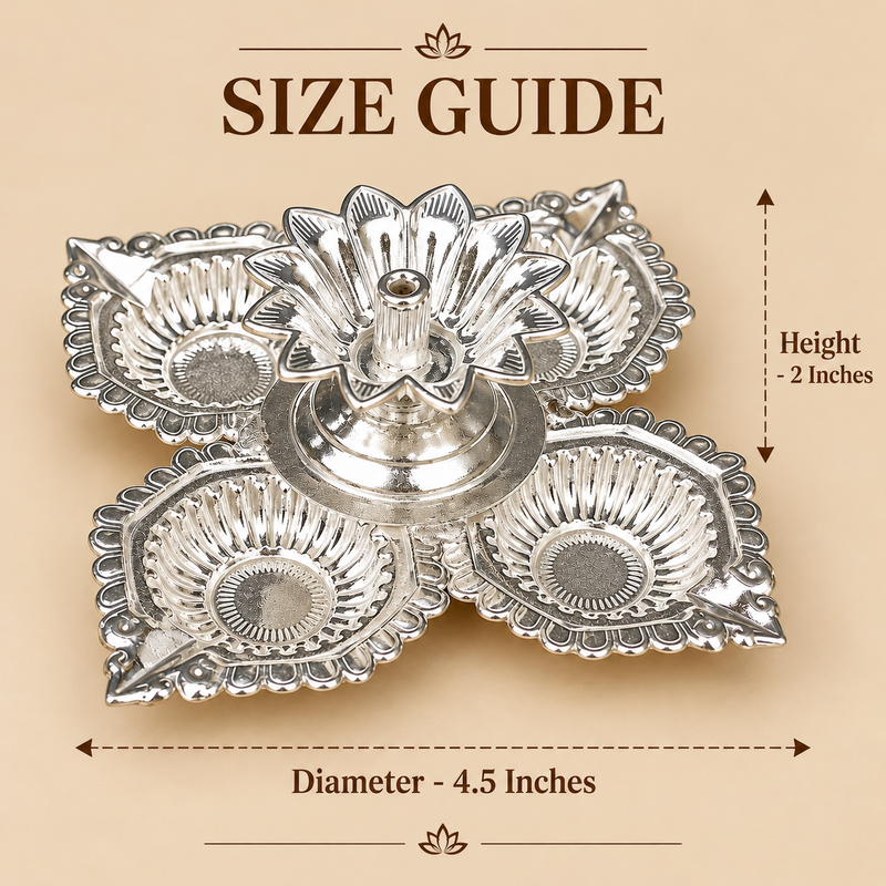 German Silver Diya size guide showing approximately 4.5 inch diameter and 2 inch height, featuring four decorative leaf shaped oil lamp cups surrounding a raised flower shaped central holder with a polished silver finish, displayed on a warm beige background to help customers understand the compact dimensions for pooja rooms, Diwali celebrations, festive decoration, traditional ceremonies and gifting.