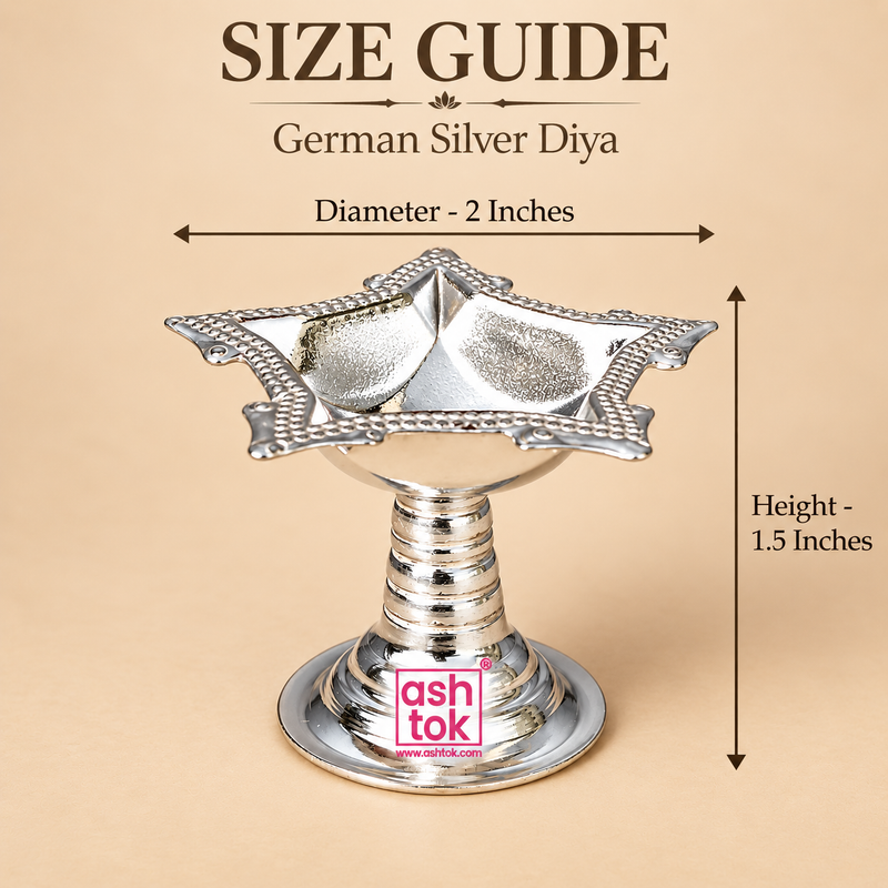 Size guide image of a German Silver Diya displayed on a beige studio background with clear measurement arrows and text, showing the diameter as 2 inches and the height as 1.5 inches, while also presenting the diya with its polished silver finish, square floral bowl, decorative pointed corners, beaded rim, ringed stem and circular pedestal base, helping customers understand the product size, compact form and proportions before purchase for pooja use or gifting.
