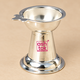 Top angle product image of a traditional German Silver Diya placed against a premium beige background, clearly showing the inner bowl shape, polished reflective interior, flared circular rim, side wick-holder extension, conical body and wide flared base, photographed in soft even lighting to display the design and proportions of the diya from above, useful for understanding the bowl depth and overall product styling for puja use, festive lighting and devotional settings.