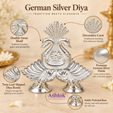 German Silver Diya features image highlighting the double swan motif, decorative crest, polished German silver finish, twin leaf shaped diya bowls and stable pedestal base, with close-up views emphasizing the ornamental detailing, elegant craftsmanship and traditional design suitable for pooja, spiritual decor, festive gifting and home mandir arrangements.