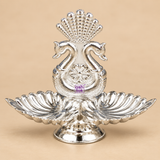 German Silver Diya and Puja Deepam with an elegant double swan motif, twin leaf shaped diya bowls, decorative fan shaped crest and polished silver finish, displayed from the front on a clean warm beige background, suitable for daily pooja, home mandir decoration, festive rituals, Diwali celebrations, spiritual use, traditional gifting and decorative worship settings.