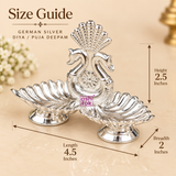 German Silver Diya size guide showing approximately 4.5 inch length, 2 inch breadth and 2.5 inch height, featuring a decorative double swan centerpiece, twin leaf shaped diya bowls and a polished silver finish, presented on a beige background with measurement arrows to help customers understand the size for pooja room use, festive decoration, gifting and home temple display.