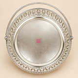Top view of a German Silver Flower Butti showing the round engraved base with detailed floral and paisley inspired patterns, surrounding ornamental cutwork border and curved carrying handle, photographed against a clean beige studio background to clearly display the interior design and decorative craftsmanship for flower arrangements, pooja accessories, gifting and festive presentation.