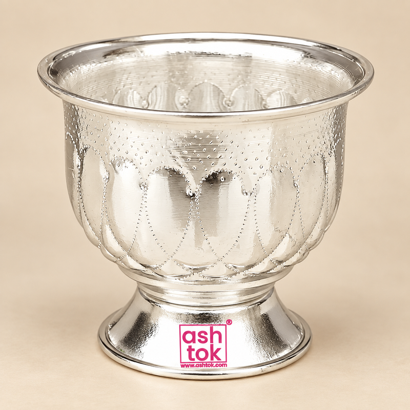 Traditional German Silver Gandham Ginni and Sindoor Holder with a polished neutral silver finish, wide flared rim, rounded bowl-shaped body, embossed floral and petal-inspired decorative pattern, fine dotted detailing and a short circular pedestal base, photographed as a clean front-facing product image on a premium beige studio background with soft lighting and natural reflections, suitable for storing sindoor, gandham, kumkum, sandalwood paste and other small pooja essentials for daily worship, home mandi