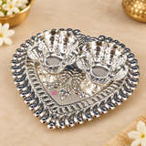 Side angle view of German Silver Haldi Kumkum Holder displaying the height of the two attached floral bowls, heart-shaped base tray, detailed decorative edging and polished reflective finish, suitable for traditional pooja use, haldi kumkum ceremonies, wedding rituals, festive celebrations and return gifting