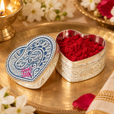 German Silver Heart-Shaped Kumkum Box shown open in a warm traditional pooja setting and filled with bright red kumkum powder, with the engraved heart-shaped lid placed nearby and surrounded by tasteful flowers and festive ritual accessories, demonstrating practical use as a compact kumkum, roli or sindoor container for daily worship, festive puja, wedding functions, religious ceremonies and traditional Indian occasions without any deity idol in the scene.